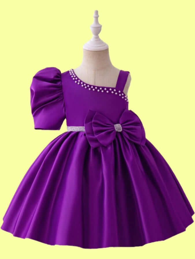 Purple princess party dress for girls with one-shoulder design, puff sleeve, and large bow at waist.